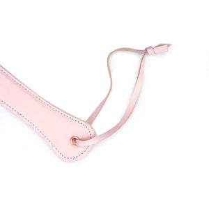 Paddle en cuir rose de la collection Fairy, confectionné en cuir d'agneau blanc et rose avec accents or rose. Un accessoire BDSM raffiné pour des jeux de fessée contrôlés et élégants.
