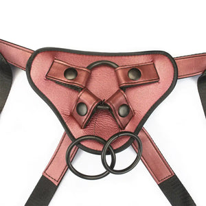 Harnais Strap-On Pink LIEBE SEELE avec base structurée rose, sangles noires réglables et anneaux métalliques, présenté à plat sur fond blanc, vue produit détaillée