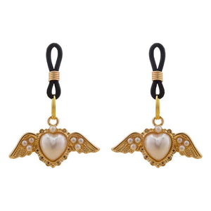 Pinces pour tétons Angel de la marque Liebe Seele, ornées de cœurs ailés dorés et de perles, reliées par des attaches noires, présentées sur fond clair dans l’univers Brigade Mondaine Paris.