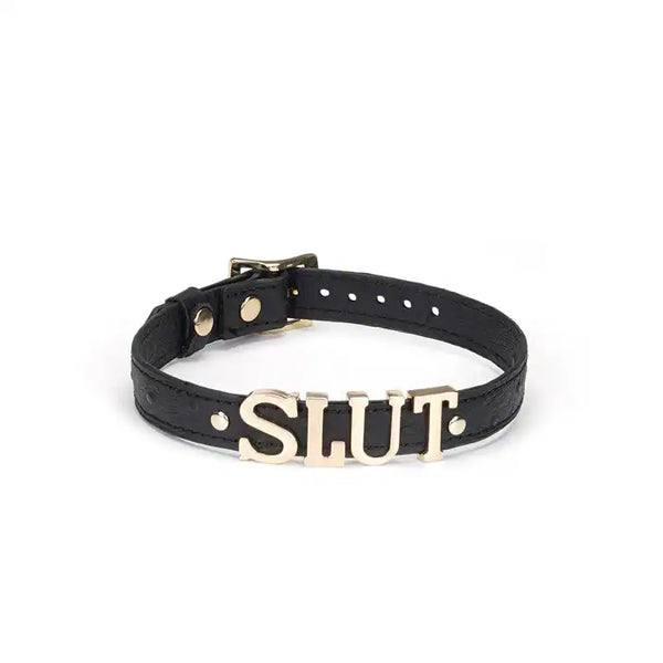 Choker en cuir noir embossé avec lettres argentées SLUT et finitions dorées. Accessoire ajustable, souple et confortable, parfait pour jeux BDSM et tenues fétichistes.