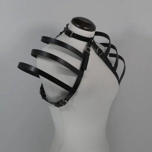 Vue de côté du harnais 73863 en cuir sur mannequin blanc, mettant en avant les lanières flottantes sur les épaules et le design sculptural du harnais. Le choker ajustable relié à l'ensemble est également visible, offrant une silhouette audacieuse et moderne.