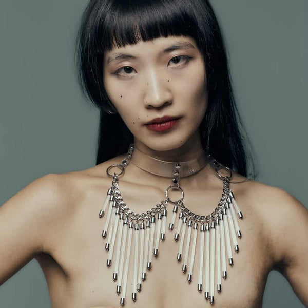 Modèle portant le Cosmic Choker Perlensau en matière transparente avec chaînes métalliques et pampilles suspendues, proposé par Brigade Mondaine Paris.