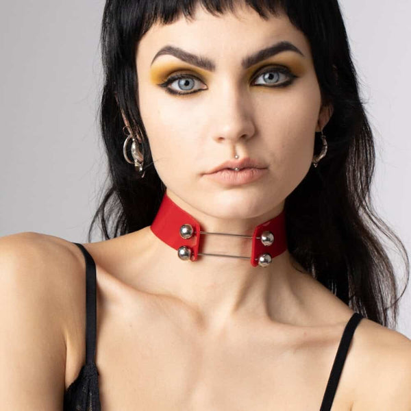 Modèle portant le Industrial Choker rouge Perlensau en cuir avec tiges métalliques et sphères argentées, proposé par Brigade Mondaine Paris.