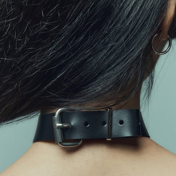 Modèle portant le Industrial Choker Perlensau en cuir noir avec éléments métalliques argentés, proposé par Brigade Mondaine Paris.