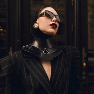 Mannequin portant le collier Posture Hold en cuir noir RE:STRICT chez Brigade Mondaine Paris, pièce rigide couvrant le cou, anneau métallique central, porté avec un top en mesh noir en studio.