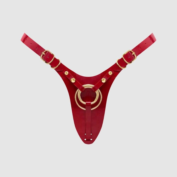 Harnais de pegging STRAP-ON-ME en cuir rouge avec anneau central doré et sangles réglables, sélection Brigade Mondaine Paris.