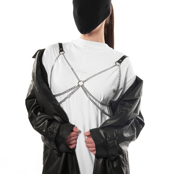 Harnais dos en cuir noir avec chaînes métalliques porté sur t-shirt blanc