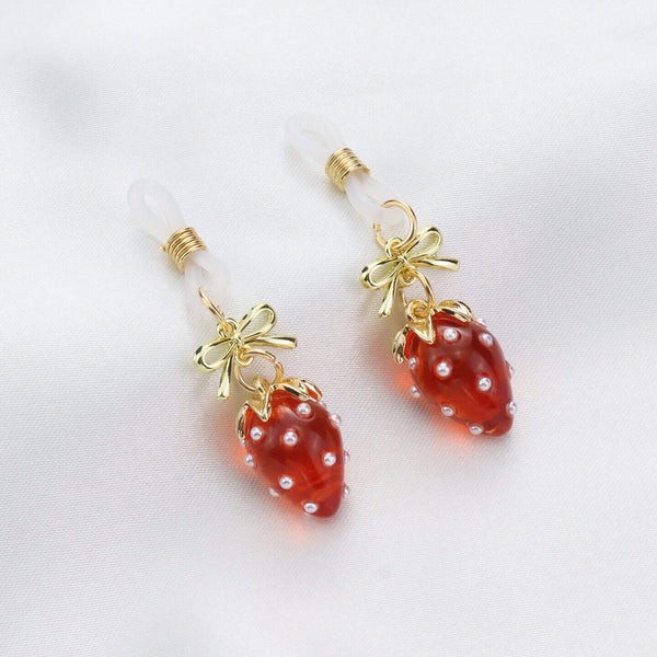 Pinces pour tétons Fraises de la marque Liebe Seele, ornées de breloques fraise rouges translucides et d’éléments dorés, présentées sur fond clair dans l’univers Brigade Mondaine Paris.