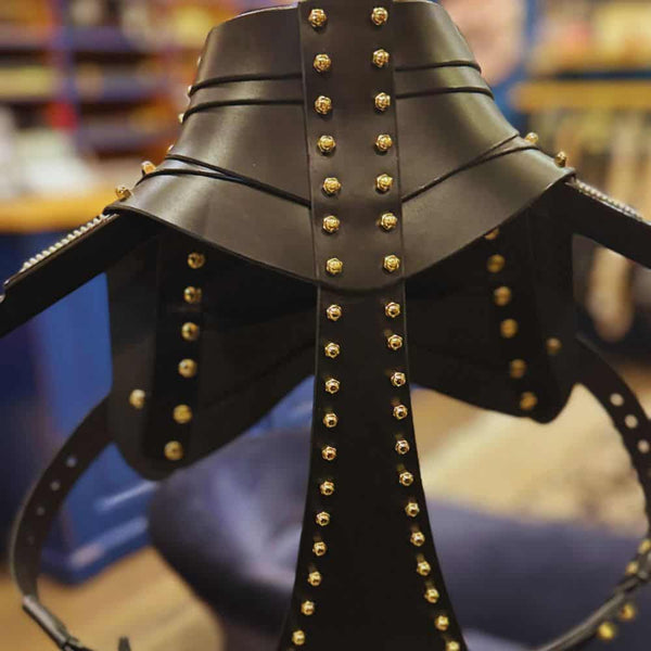 Holster d’épaule en cuir noir signé Úna Burke, inspiré des étuis pour armes à feu, avec raccords en laiton massif recouverts d’or et vis en laiton, créant une pièce rock chic et structurée, portée par des icônes comme Janet Jackson et Rihanna.