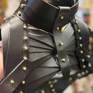 Holster d’épaule en cuir noir signé Úna Burke, inspiré des étuis pour armes à feu, avec raccords en laiton massif recouverts d’or et vis en laiton, créant une pièce rock chic et structurée, portée par des icônes comme Janet Jackson et Rihanna.