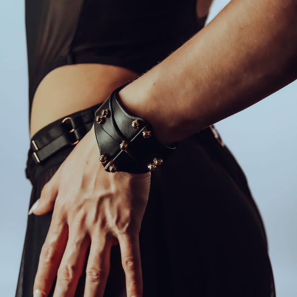 Bracelet de type manchette signée Una Burke en cuir noir de vache tanné végétal les raccords en laiton massif recouverts d’or et les vis en laiton.