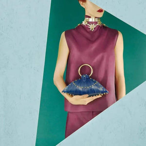 Femme portant un sac à main Une burke en cuir bleu sur un fond bleu turquoise.