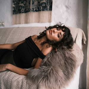 Body noir Undress Code Libra à épaules dégagées, porté par un modèle tenant une coupe de champagne, sélection Brigade Mondaine Paris.