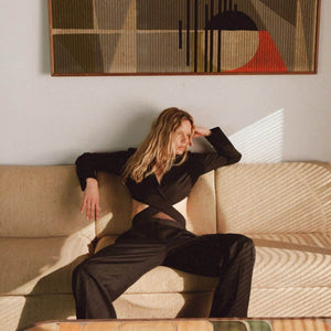 Photo d'une Femme Assise de Devant portant un Body Blazer avec résille et Croisé avec un Pantalon couleur Noir