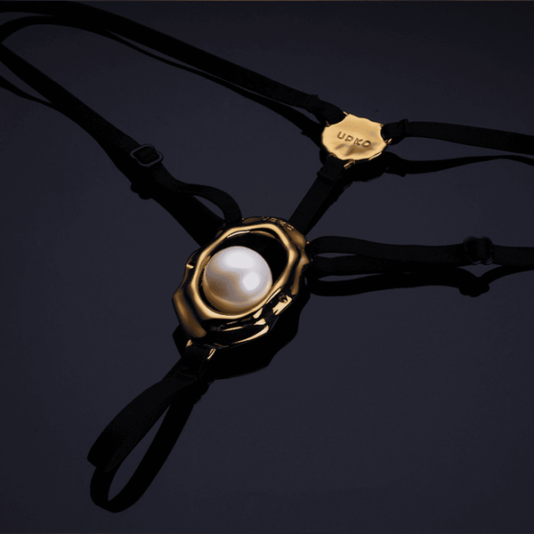 Bijou clitoridien “Moist Eyes” de UPKO avec stimulateur ergonomique et perle roulante. G-String ajustable, détails dorés, alliage de zinc hypoallergénique pour une stimulation et un confort optimaux.