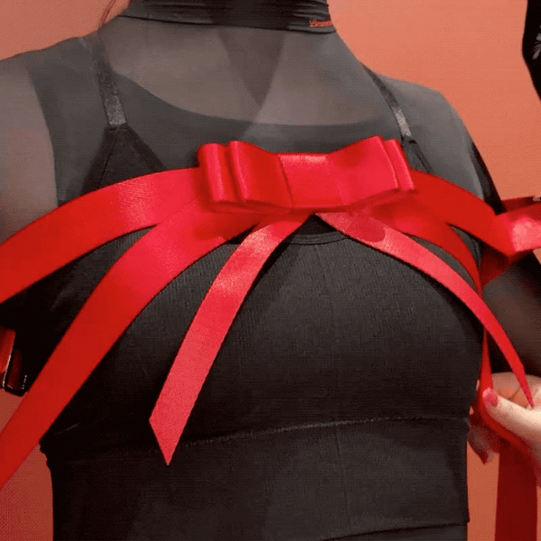 Harnais Bowknot UPKO en sangles noires avec nœud papillon central, encadrant poitrine et bras, équipé d’attaches Velcro – harnais haut du corps esthétique et fonctionnel.