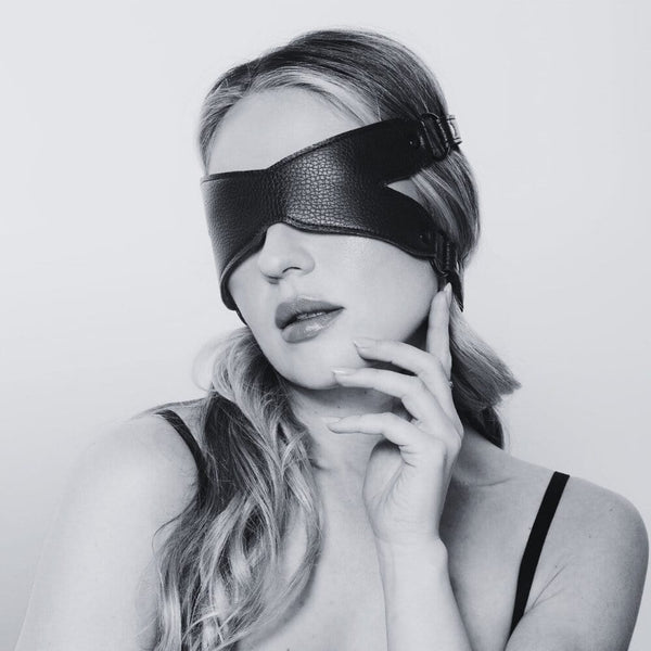 Bandeau X en cuir noir avec sangles ajustables et boucles métalliques, accessoire de bondage proposé par Brigade Mondaine Paris.