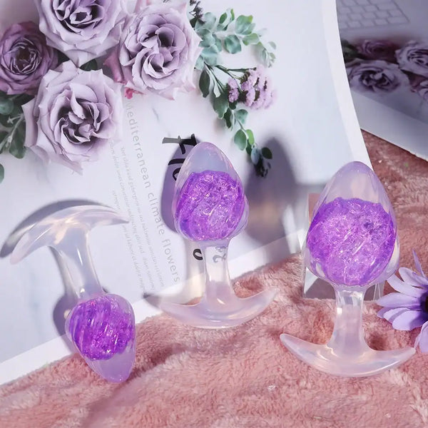 Plug en silicone violet LIEBE SEELE avec surface spiralée et base transparente évasée, tenu en main sur fond blanc, vue produit détaillée