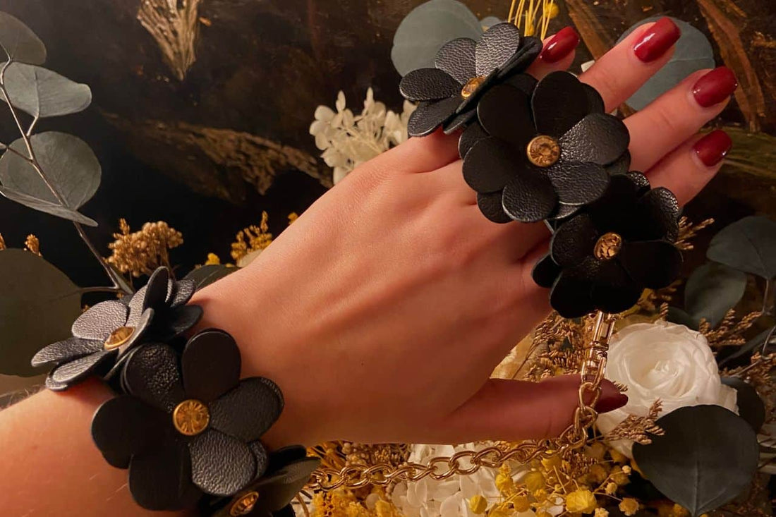 Main portant les deux menottes en cuir noir au design fleur.