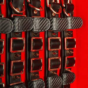 Coffret BDSM ouvert en cuir noir avec intérieur rouge, présentant un ensemble d’accessoires assortis comprenant menottes, sangles, cravaches et chaînes, disposés de manière ordonnée dans une esthétique luxueuse.