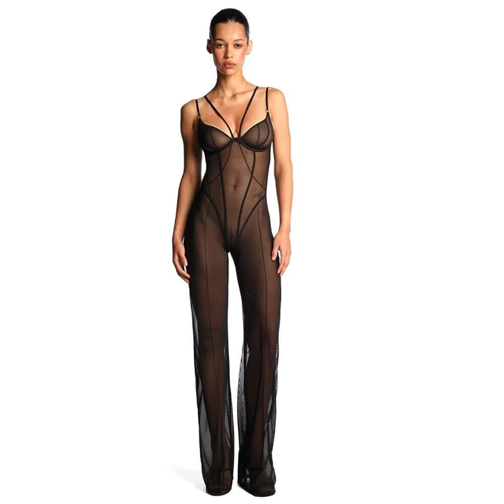 Catsuit ANOESES en mesh noir porté par un modèle féminin debout, coupe près du corps avec bretelles fines, lignes graphiques verticales et jambes longues transparentes, esthétique fétiche haut de gamme Brigade Mondaine Paris.