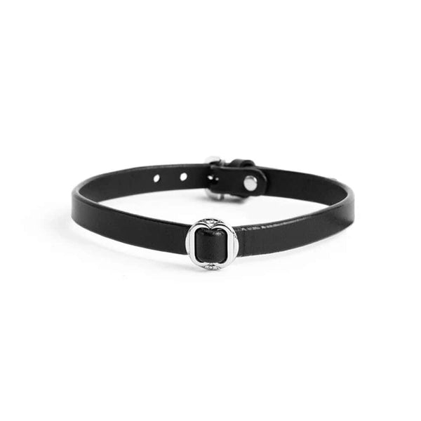 Collier ANOESES en cuir noir présenté à plat, bande fine avec anneau métallique central et fermeture réglable à boutons-pression, esthétique fétiche haut de gamme Brigade Mondaine Paris.