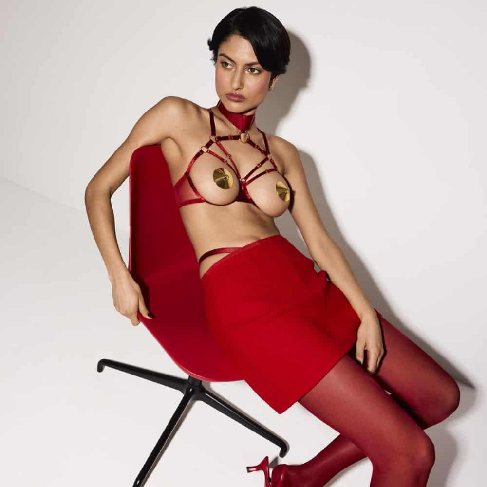 Femme s'asseoir portant le Soutien-Gorge Ouvert Bondage en rouge.