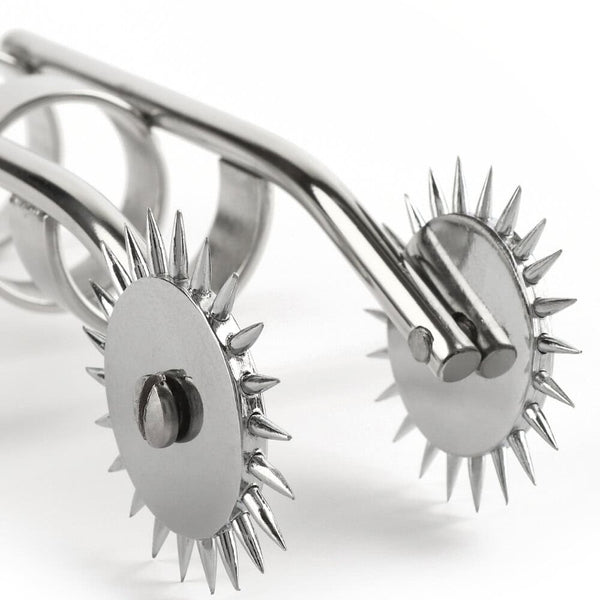 Roulette de Wartenberg à doigts en acier poli avec deux roues crantées et anneaux de maintien, présentée sur fond blanc dans une esthétique minimaliste et professionnelle.
