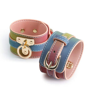 Menottes de chevilles en cuir multicolore Rainbow avec doublure rose, coutures contrastées et boucles dorées, présentées sur fond blanc dans une esthétique élégante.