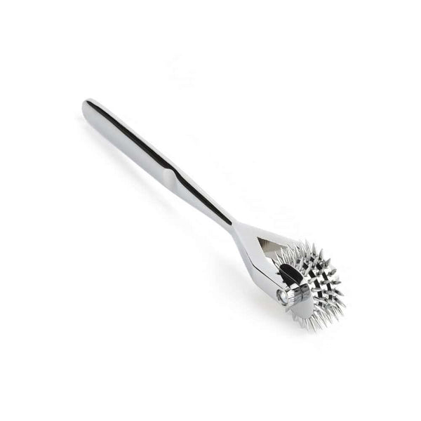 Roulette de Wartenberg en acier inoxydable brillant avec roulettes dentelées, design médical revisité, présentée par Brigade Mondaine Paris sur fond clair.
