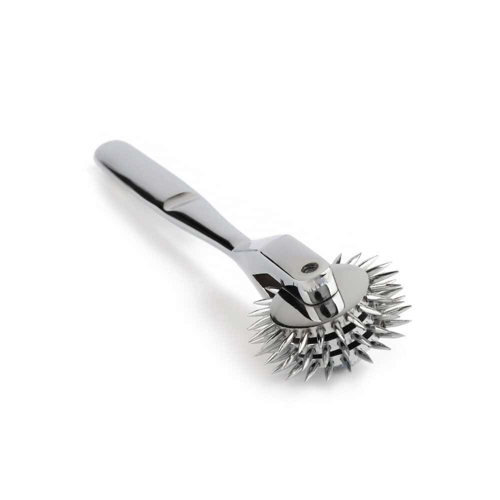 Roulette de Wartenberg en acier inoxydable brillant avec roulettes dentelées, design médical revisité, présentée par Brigade Mondaine Paris sur fond clair.