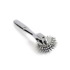 Roulette de Wartenberg en acier inoxydable brillant avec roulettes dentelées, design médical revisité, présentée par Brigade Mondaine Paris sur fond clair.