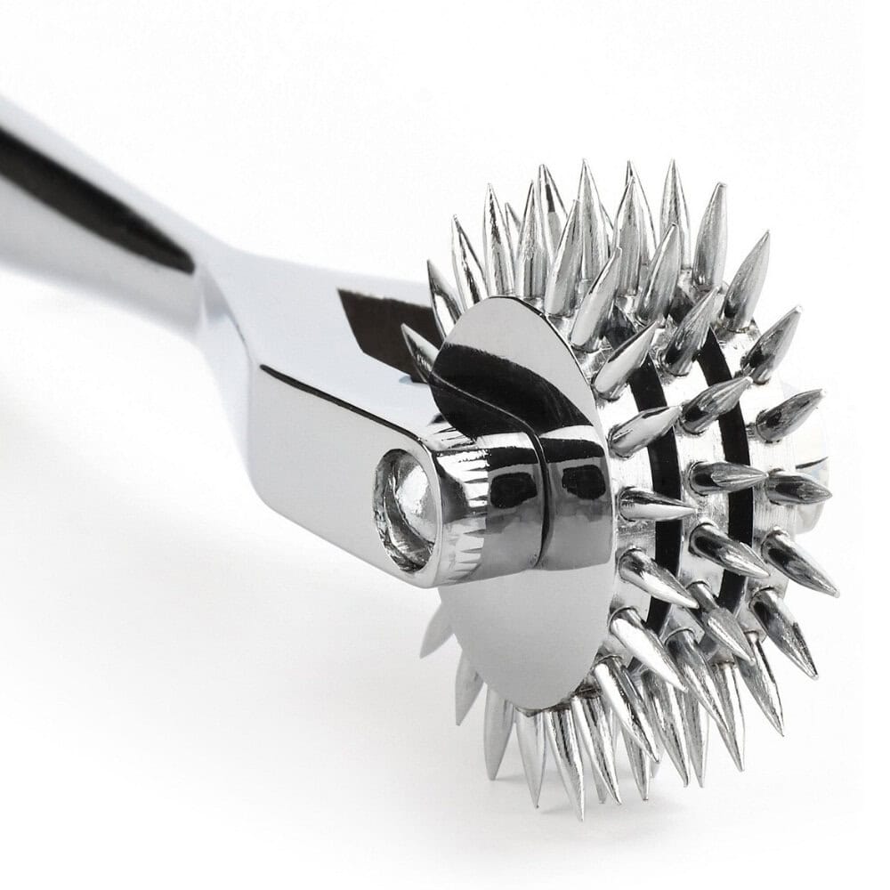 Roulette de Wartenberg en acier inoxydable brillant avec roulettes dentelées, design médical revisité, présentée par Brigade Mondaine Paris sur fond clair.
