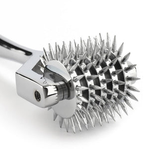 Roulette de Wartenberg en acier inoxydable brillant avec roulettes dentelées, design médical revisité, présentée par Brigade Mondaine Paris sur fond clair.