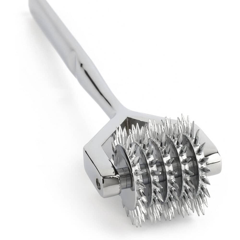 Roulette de Wartenberg en acier inoxydable brillant avec roulettes dentelées, design médical revisité, présentée par Brigade Mondaine Paris sur fond clair.