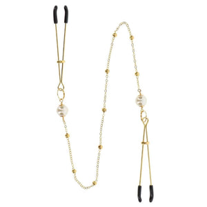 Pinces à tétons dorées avec chaîne fine et perles, portées sur le buste, accessoire sensuel proposé par Brigade Mondaine Paris.