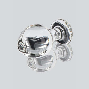 Plug anal en verre transparent poli à finition brillante, forme sphérique avec base évasée, présenté sur fond blanc, sélection Brigade Mondaine Paris.