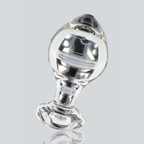 Plug anal en verre transparent poli à finition brillante, forme sphérique avec base évasée, présenté sur fond blanc, sélection Brigade Mondaine Paris.