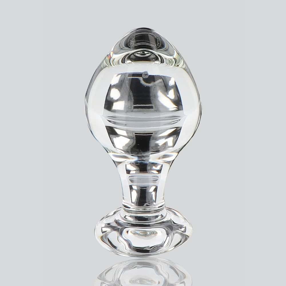 Plug anal en verre transparent poli à finition brillante, forme sphérique avec base évasée, présenté sur fond blanc, sélection Brigade Mondaine Paris.