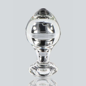 Plug anal en verre transparent poli à finition brillante, forme sphérique avec base évasée, présenté sur fond blanc, sélection Brigade Mondaine Paris.