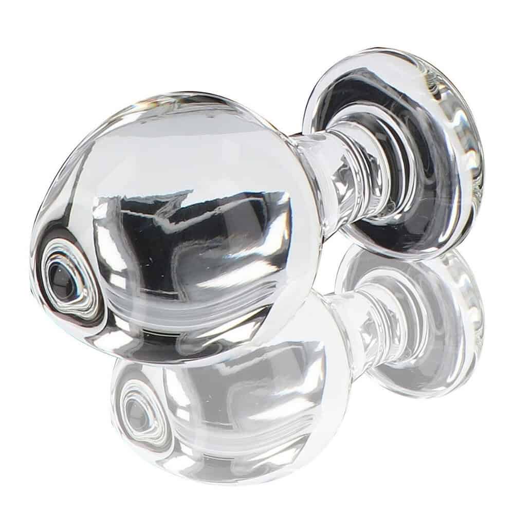 Plug anal en verre transparent poli à finition brillante, forme sphérique avec base évasée, présenté sur fond blanc, sélection Brigade Mondaine Paris.