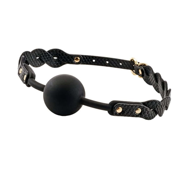 Bâillon boule BDSM composé d’une boule noire mate et de sangles en cuir noir texturé avec rivets et bouclerie dorée, présenté sur fond sombre dans une mise en scène élégante.