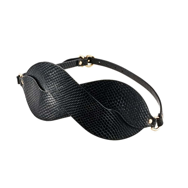 Masque BDSM en cuir noir texturé à la forme enveloppante, avec attaches réglables et bouclerie dorée, présenté sur fond noir dans une mise en scène élégante et minimaliste.