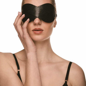 Masque BDSM en cuir noir texturé à la forme enveloppante, avec attaches réglables et bouclerie dorée, présenté sur fond noir dans une mise en scène élégante et minimaliste.