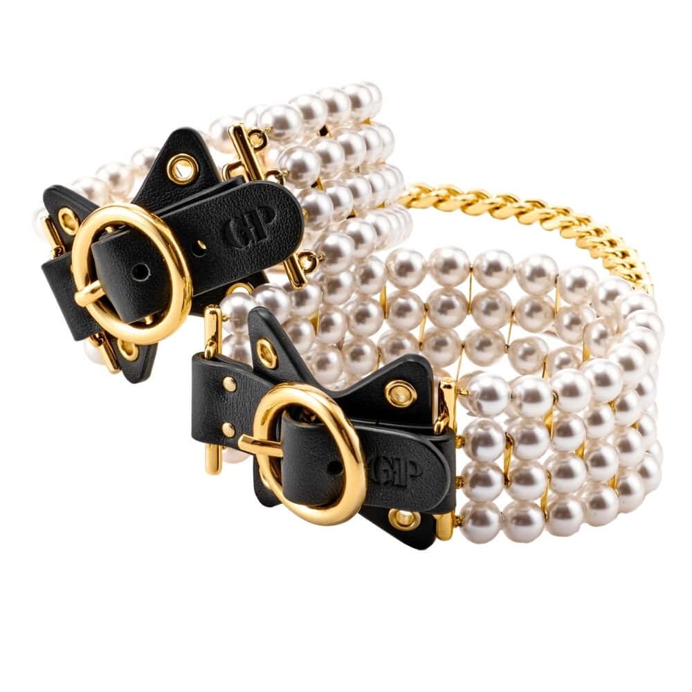 Entraves de chevilles en cuir noir ornées de perles et reliées par une chaîne dorée, portées sur modèle, proposées par Brigade Mondaine Paris.