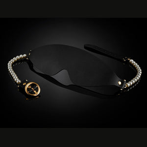Masque BDSM en cuir noir avec bordures perlées et finitions dorées, accessoire de privation visuelle haut de gamme sélectionné par Brigade Mondaine Paris.