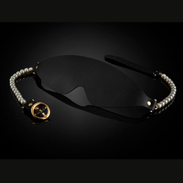 Masque BDSM en cuir noir avec bordures perlées et finitions dorées, accessoire de privation visuelle haut de gamme sélectionné par Brigade Mondaine Paris.
