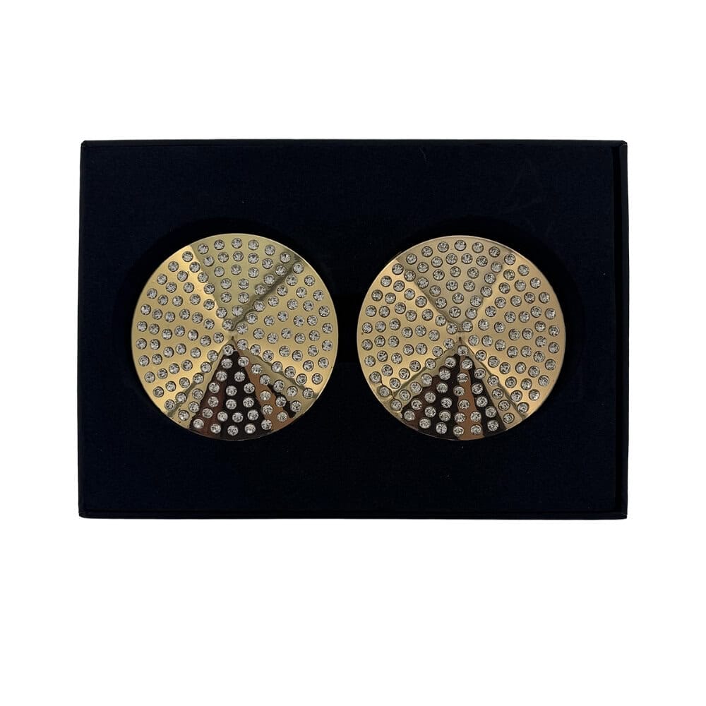 Paire de cache-tétons dorés circulaires ornés de strass brillants, présentés dans un écrin noir sur fond blanc, avec une esthétique élégante et minimaliste.