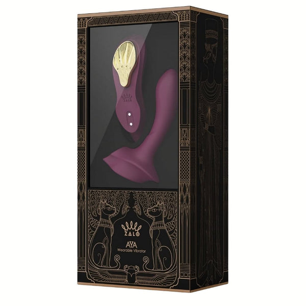 Vibromasseur portable de couleur prune avec détails dorés, design ergonomique et commandes intégrées, présenté sur fond blanc, sélection Brigade Mondaine Paris.