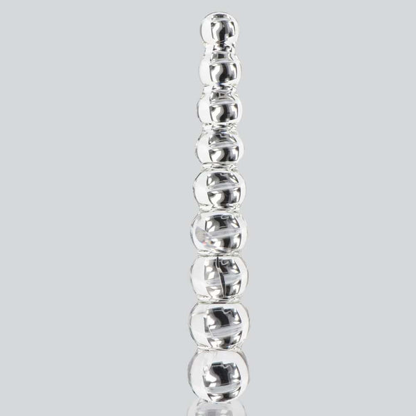 Dildo en verre transparent composé de formes sphériques alignées, présenté verticalement sur fond blanc, avec une finition lisse et brillante.